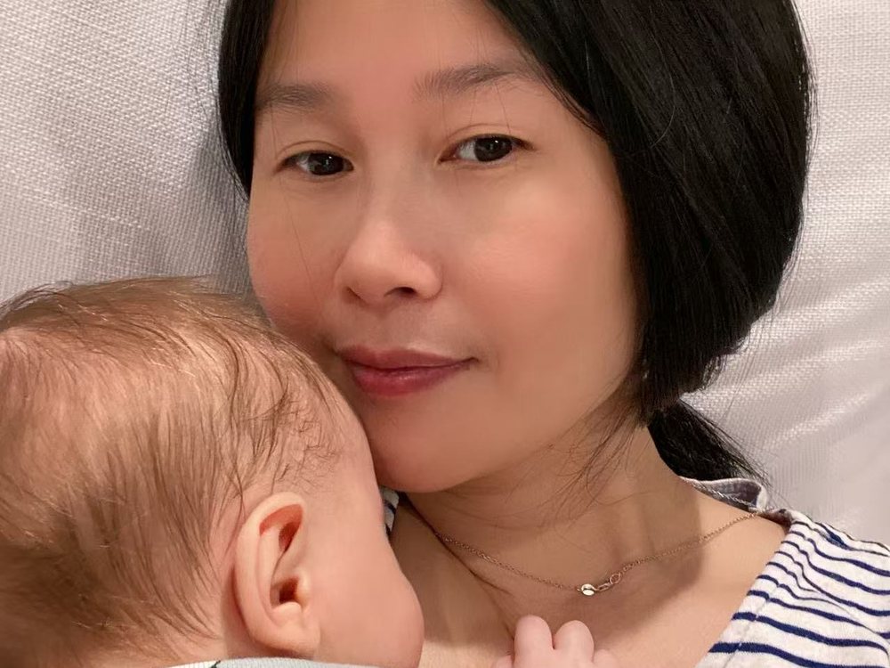 Akim holding a sleeping newborn against her shoulder