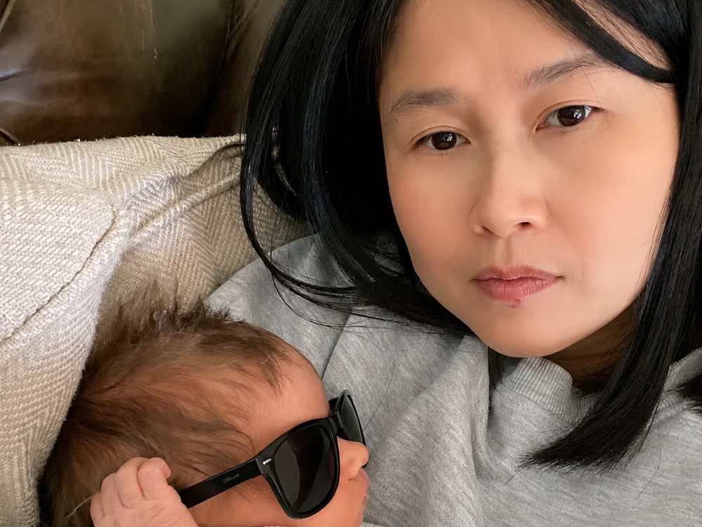 Akim resting with a newborn on a sofa