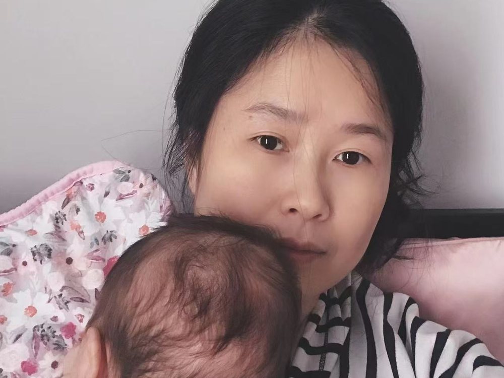 Akim settling a newborn who has fallen asleep on her